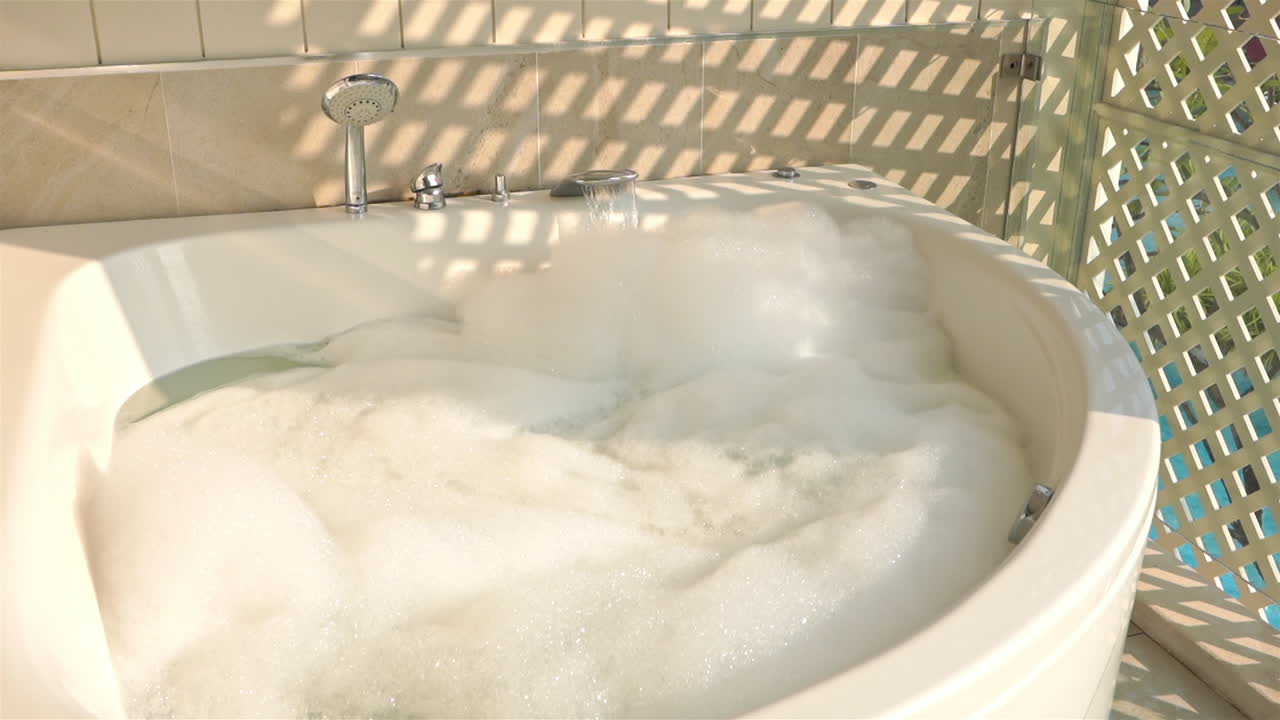A huge spa-like bathtub is being filled to the brim with bubbles and water