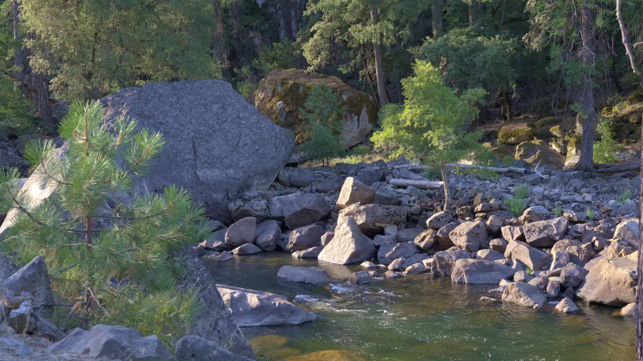Footage of a scenic river in Yosemite National Park, California, featuring giant granite boulders scattered throughout the flowing water.