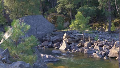 footage of a scenic river in yosemite national park, california, featuring giant granite boulders scattered throughout the flowing water.