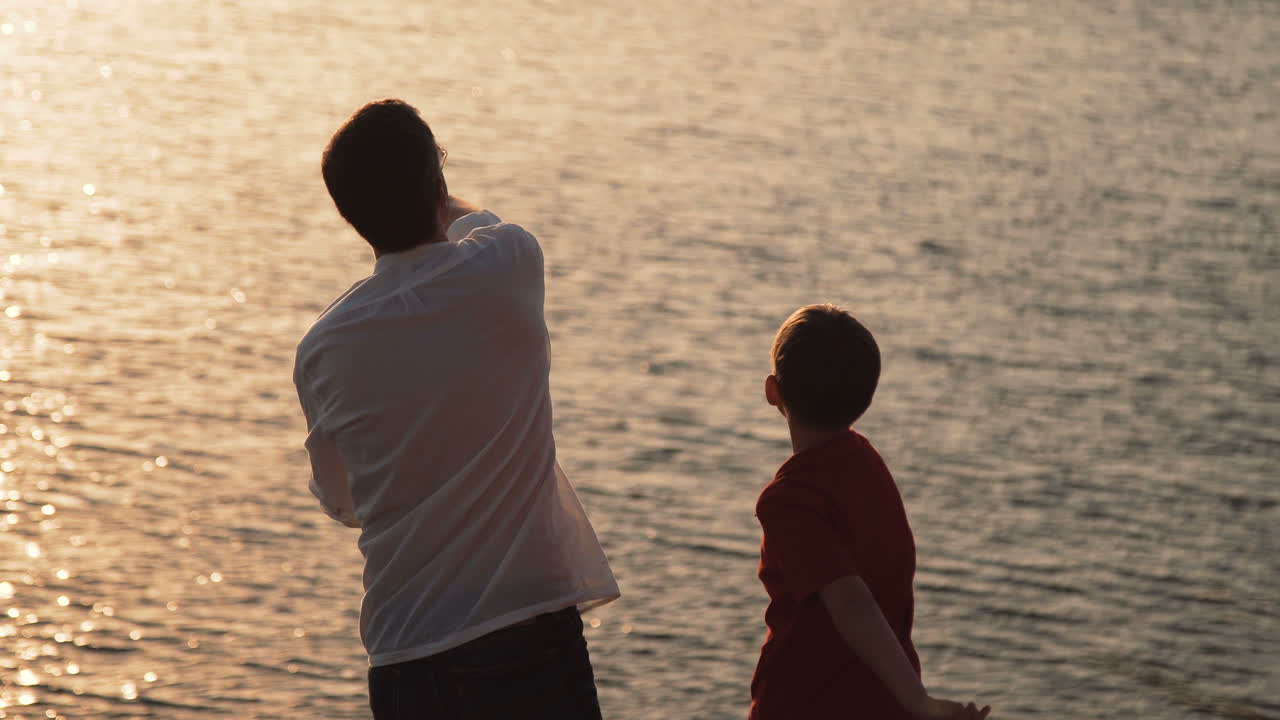 Father and Son Playing at Sunset by the River