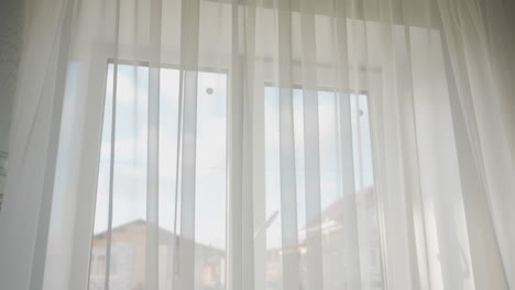 view of residential building seen through transparent white curtain from inside bright cozy kitchen morning sunlight softly filtering through sheer fabric