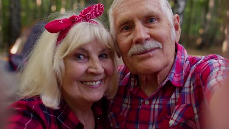 Senior-grandmother-grandfather-blogger-tourists-taking-selfie-photo-portrait-on-mobile-phone-in-wood