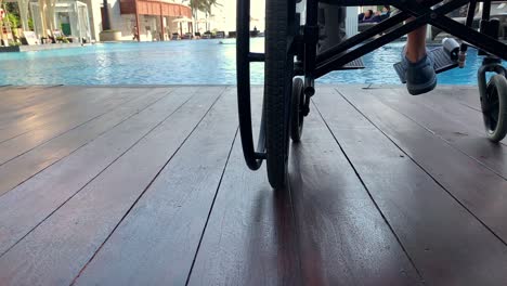 person with mobility impairment in a wheelchair by the side of a swimming pool