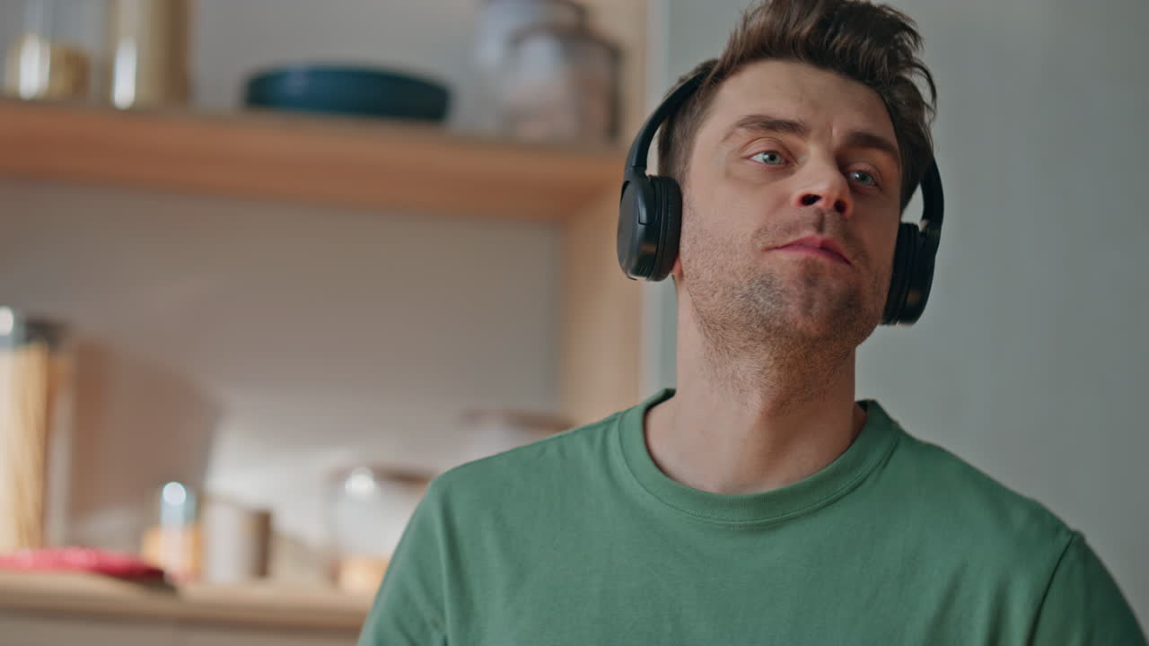 Relaxed melomaniac eating breakfast kitchen closeup. Happy guy listening music