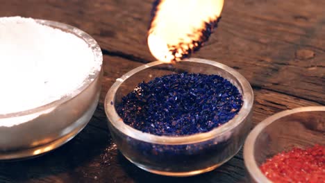 close-up of glassblower attaching colored glass to a piece of hot molten glass