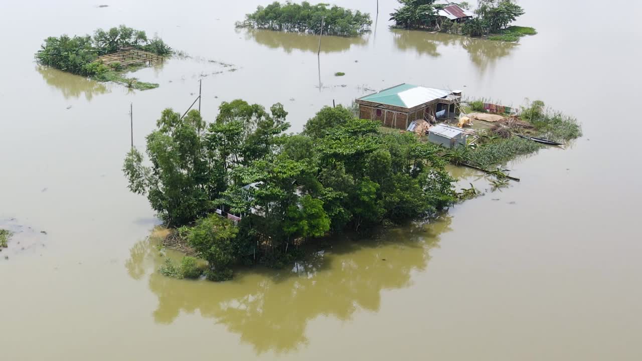 Homes and trees isolated by floodwater in a rural Bangladesh village, aerial view