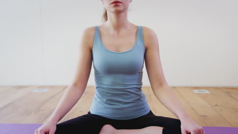 young woman doing yoga on wooden floored studio at home