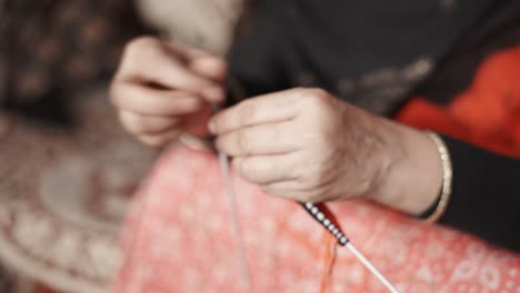 woman's hands knitting with black thread and two needle crafts