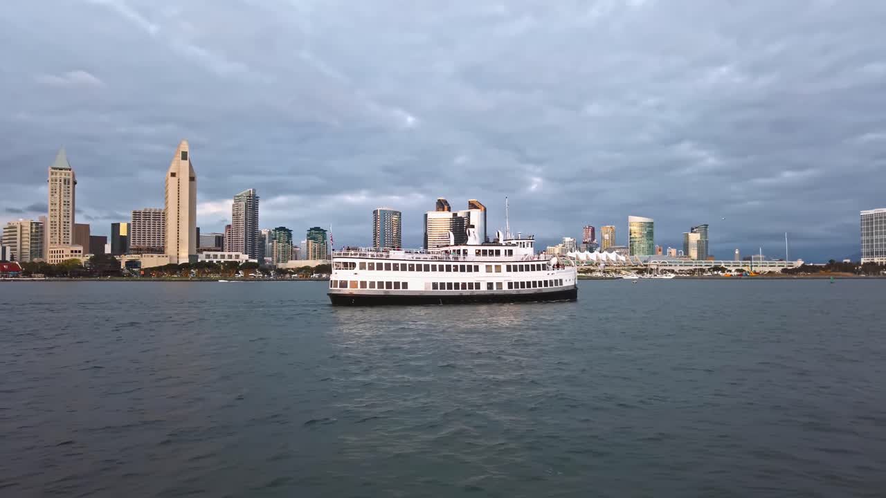 A big touristic boat floating on San Diego bay in front of downtown. Cloudy sky