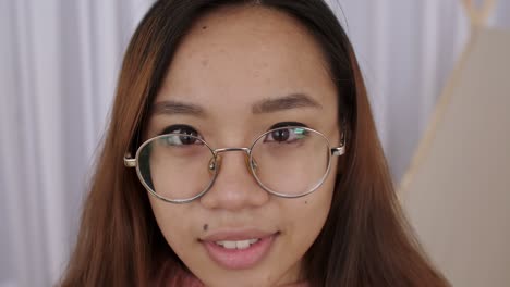 close up of middle eastern young woman face in glasses, girl, student takes pictures on a retro camera, presses the shutter. female photographer picks up the camera and presses button. slow motion