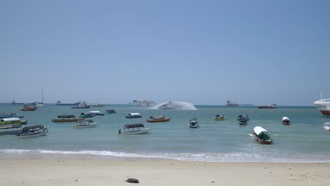 Tug-Boat-Showing-A-Ceremonial-Water-Salute-By-Spraying-Water-Into-The-Air-In-Stone-Town,-Zanzibar,-Tanzania