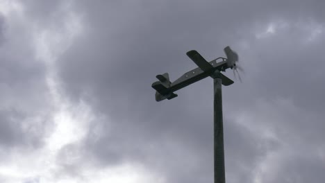 Ein-Flugzeugwetterhahn-Im-Wind,-Der-Sich-Vor-Grauen-Wolken-Mit-Dem-Wind-Bewegt