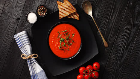Tomato-soup-in-black-bowl-with-crisp-bread-