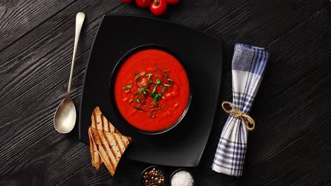 tomato soup in black bowl with crisp bread