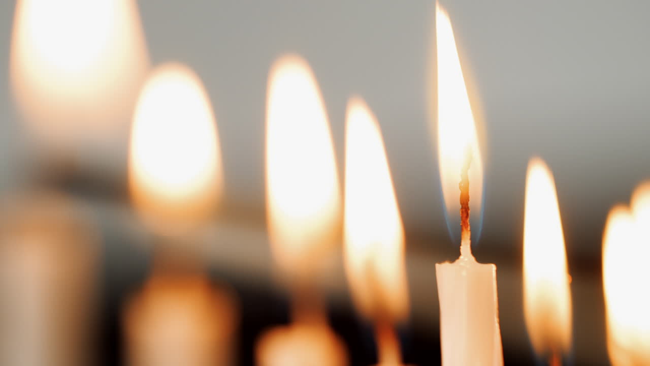 Detail shot of a group of white candles being lit for the Jewish holiday of Hanukkah, selective focus