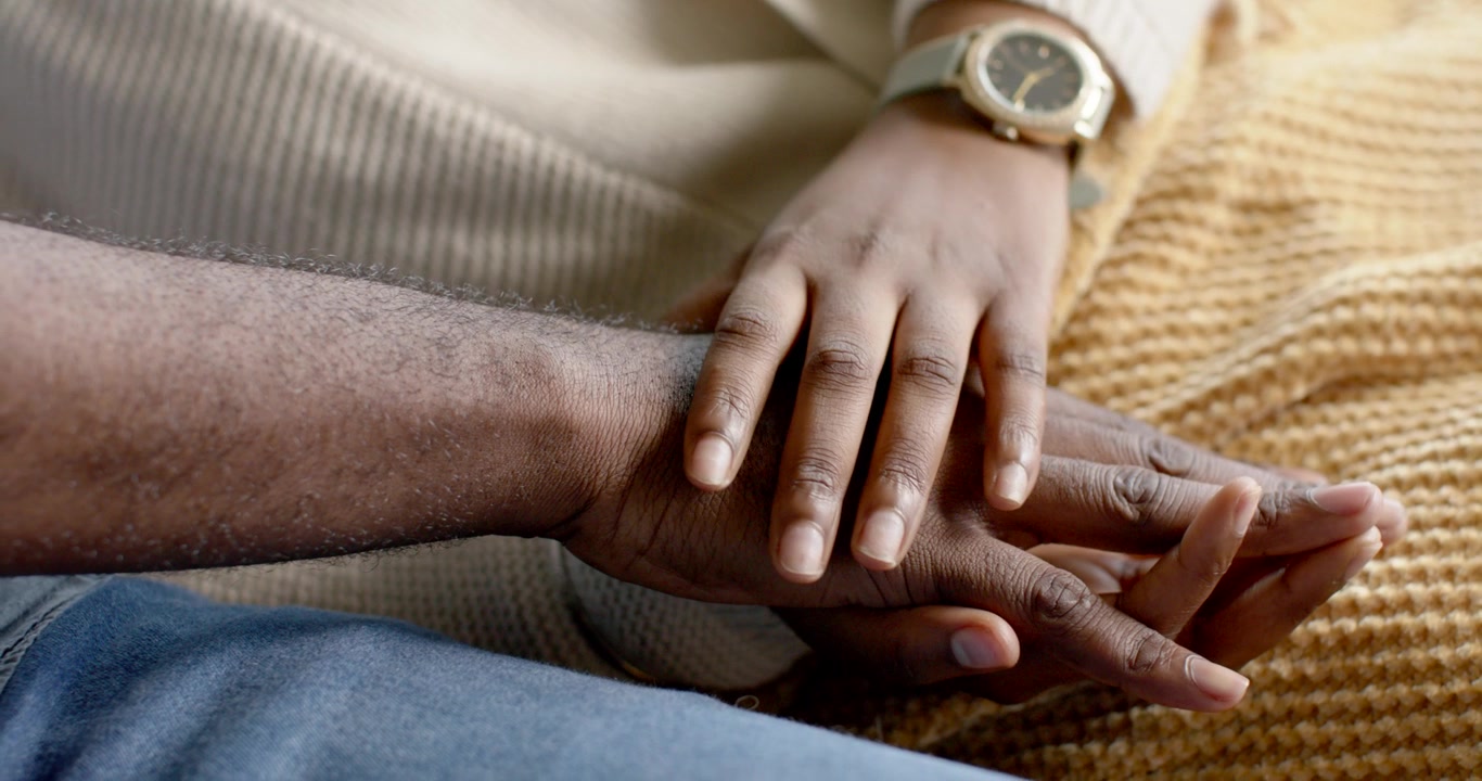 African couple, female hand with watch placing over male hand, sliding fingers for comfort at home