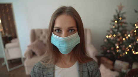 Portrait-Of-Woman-Taking-Off-The-Face-Mask-Looking-At-Camera-Smiling-Indoors-At-Home