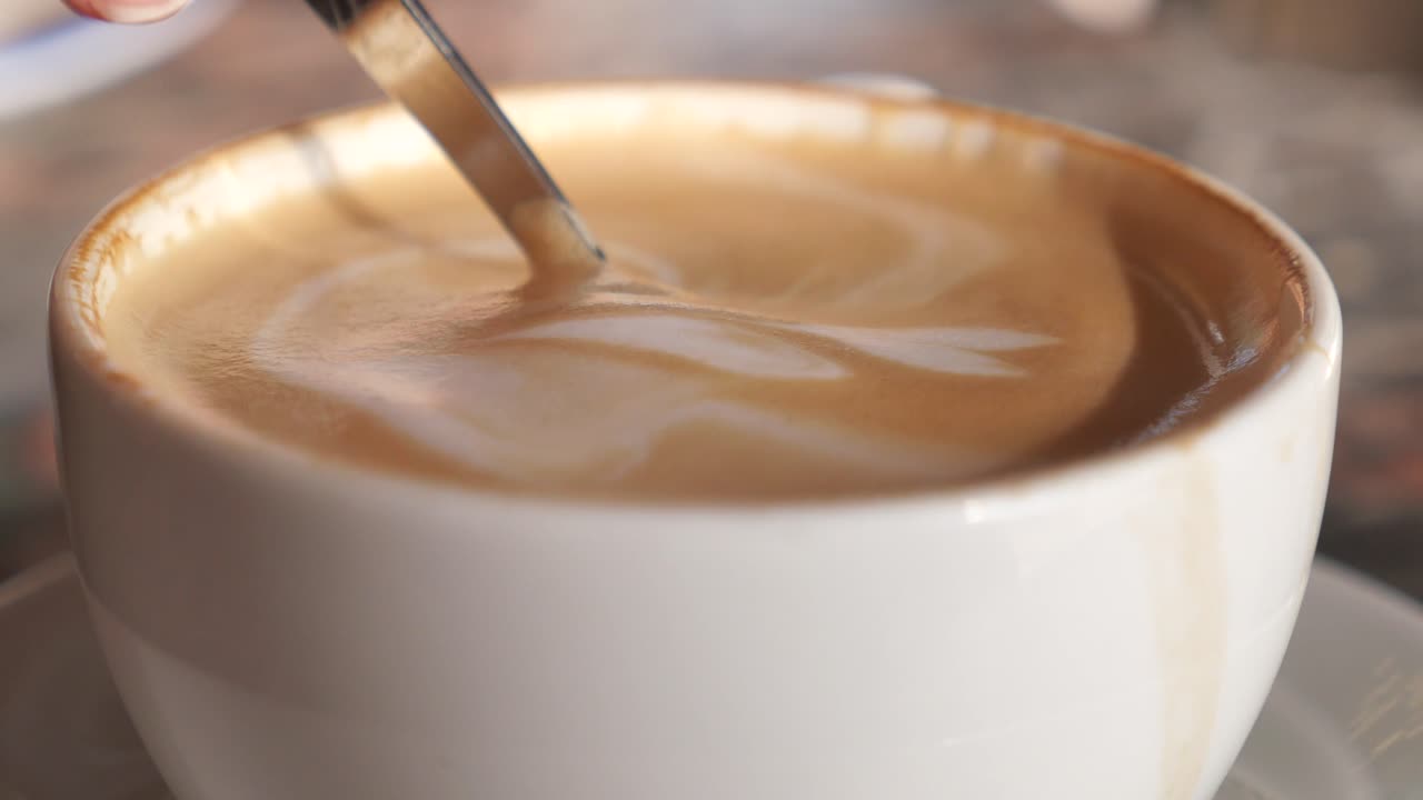 Primo piano di un latte macchiato mescolato con un cucchiaino