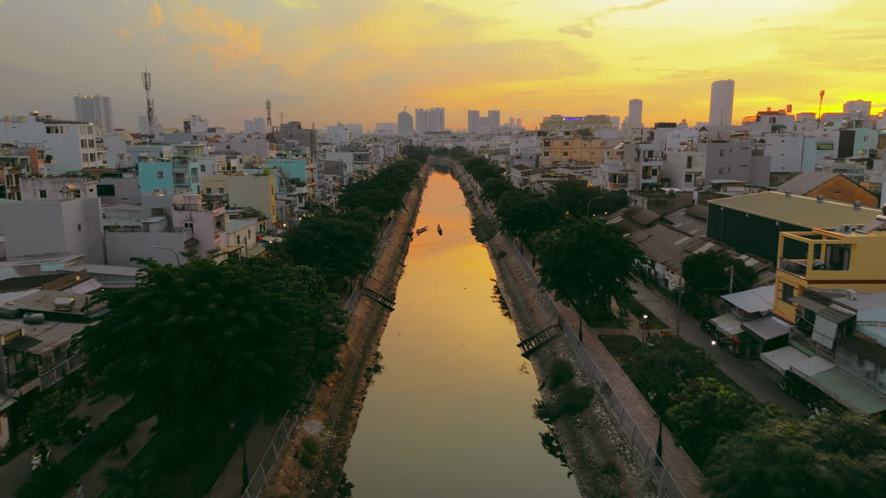 Witness the serene beauty of a city canal as the sun sets in this captivating aerial footage