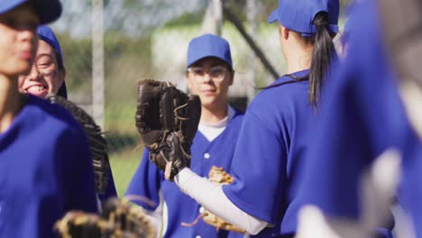 Feliz-Y-Diverso-Grupo-De-Jugadoras-De-Béisbol-Sonriendo-Y-Golpeando-Guantes-Después-Del-Partido