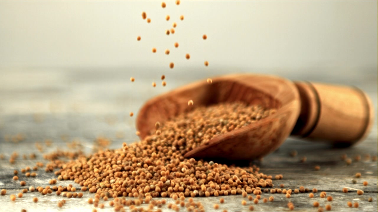 Mustard Seeds Falling in Slow Motion onto a Rustic Wooden Surface