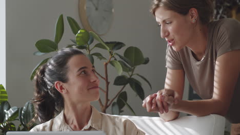 two women browsing the web on laptop and chatting at home