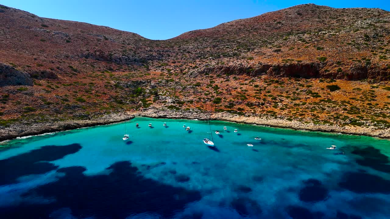 Explore a beautiful harbor surrounded by colorful hills and clear blue waters. Sailboats are gently swaying, creating a peaceful atmosphere under a bright sky