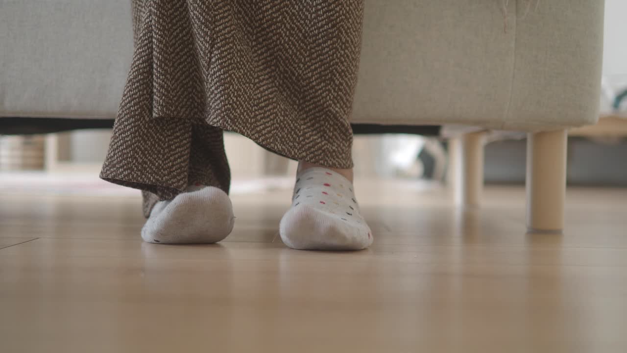 Close-up of feet in polka dot socks under furniture indoors