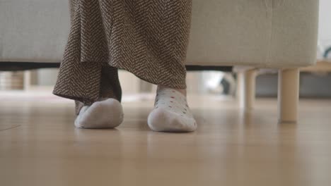 close-up of feet in polka dot socks under furniture indoors