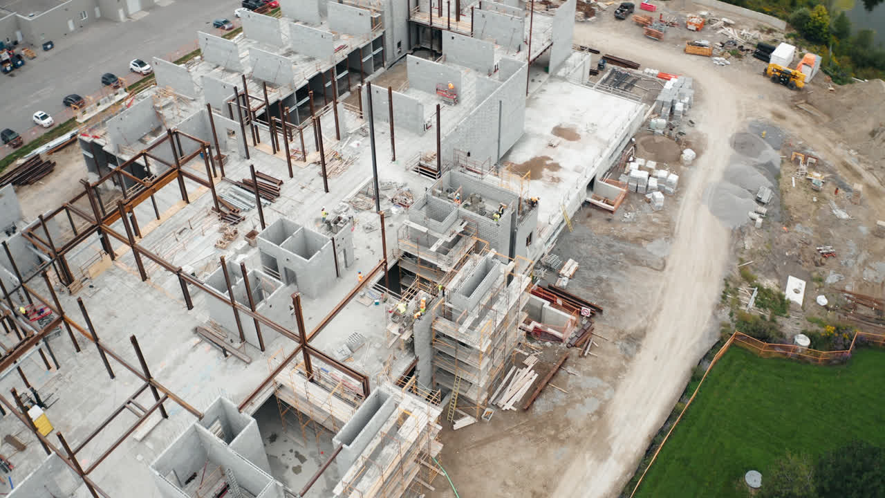 vuelo aéreo sobre un nuevo edificio comercial en desarrollo con trabajadores del sitio de construcción del sindicato empleados que operan trabajos de maquinaria pesada