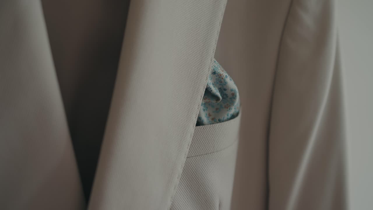 Beige suit jacket featuring a folded patterned pocket square