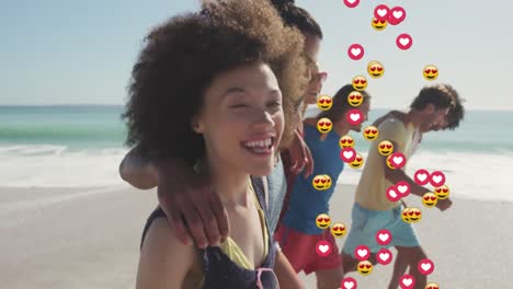 animación de corazones y emojis de amor sobre un grupo diverso de amigos felices caminando por una playa soleada