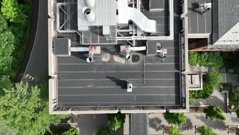 el dron se eleva por encima de los ventiladores y las tuberías de ventilación en el techo plano del edificio con el sistema hvac expuesto