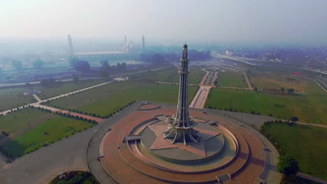 aerial rotating view of minar-e-pakistan with city and mughal`s famous badshahi mosque, a national monument located in lahore, pakistan