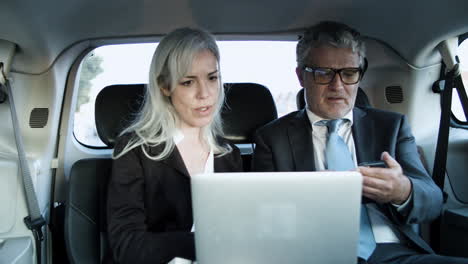 businessman talking to his coworker while calling on phone in the car