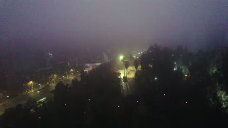 Night-aerial-view-over-the-Caupolican-terrace-on-Santa-Lucía-Hill,-a-mysterious-and-lonely-view-on-a-foggy-morning,-low-traffic