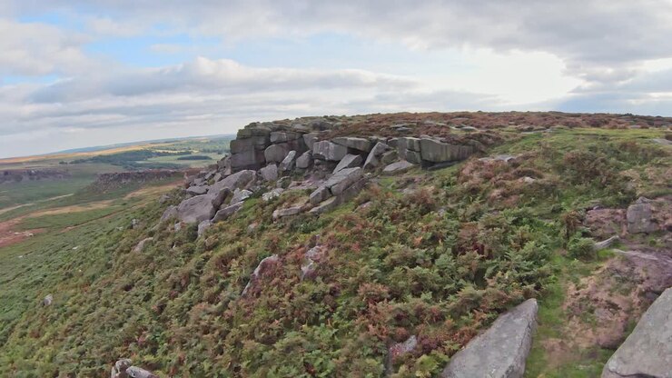 Quick flying aerial fpv soars along gritstone rocky cliffs of Stanage Edge England