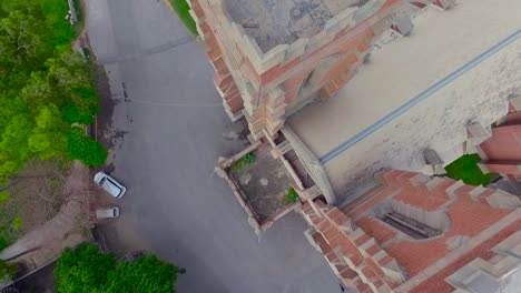 Vista-Rotacional-Aérea-De-90-Grados-De-La-Iglesia,-Una-Furgoneta-Estacionada-En-La-Parte-Delantera-De-Una-Antigua-Iglesia-Hermosa