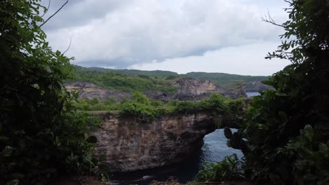 natural arch bridge of lush green broken beach on nusa penida