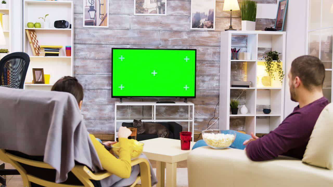 Couple watching television with green screen in living room
