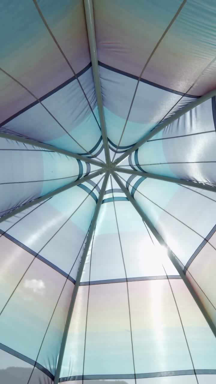Vista dal basso di un baldacchino in tessuto colorato illuminato dal sole