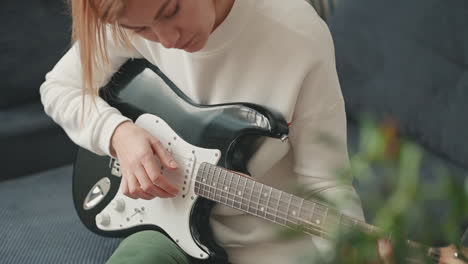 una mujer pelirroja aprendiendo a tocar la guitarra eléctrica