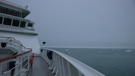 cruise ship on arctic expedition sailing in cold sea water with misty horizon, passenger pov