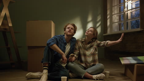 young family eating in repaired house. couple sitting on floor in new apartment.