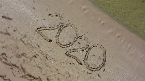 twenty twenty written in the sand and spinning counterclockwise making it a crazy year