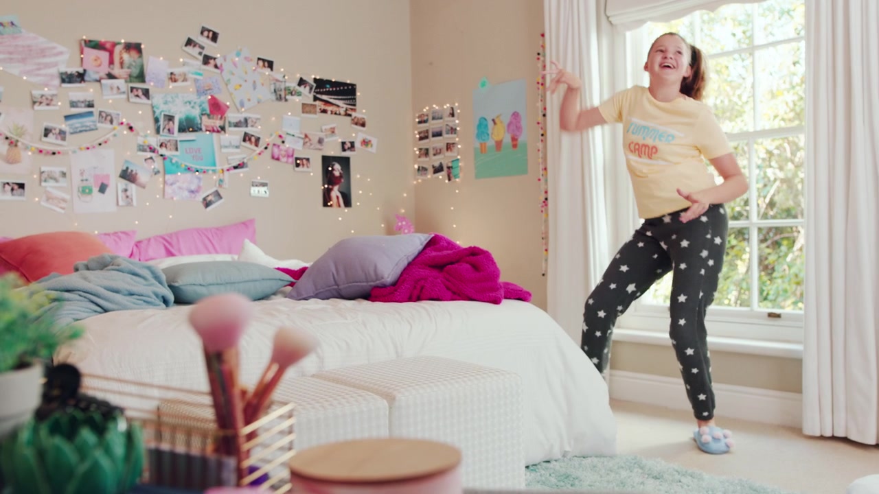 Happy Young Girl Dancing and Singing in Her Bedroom