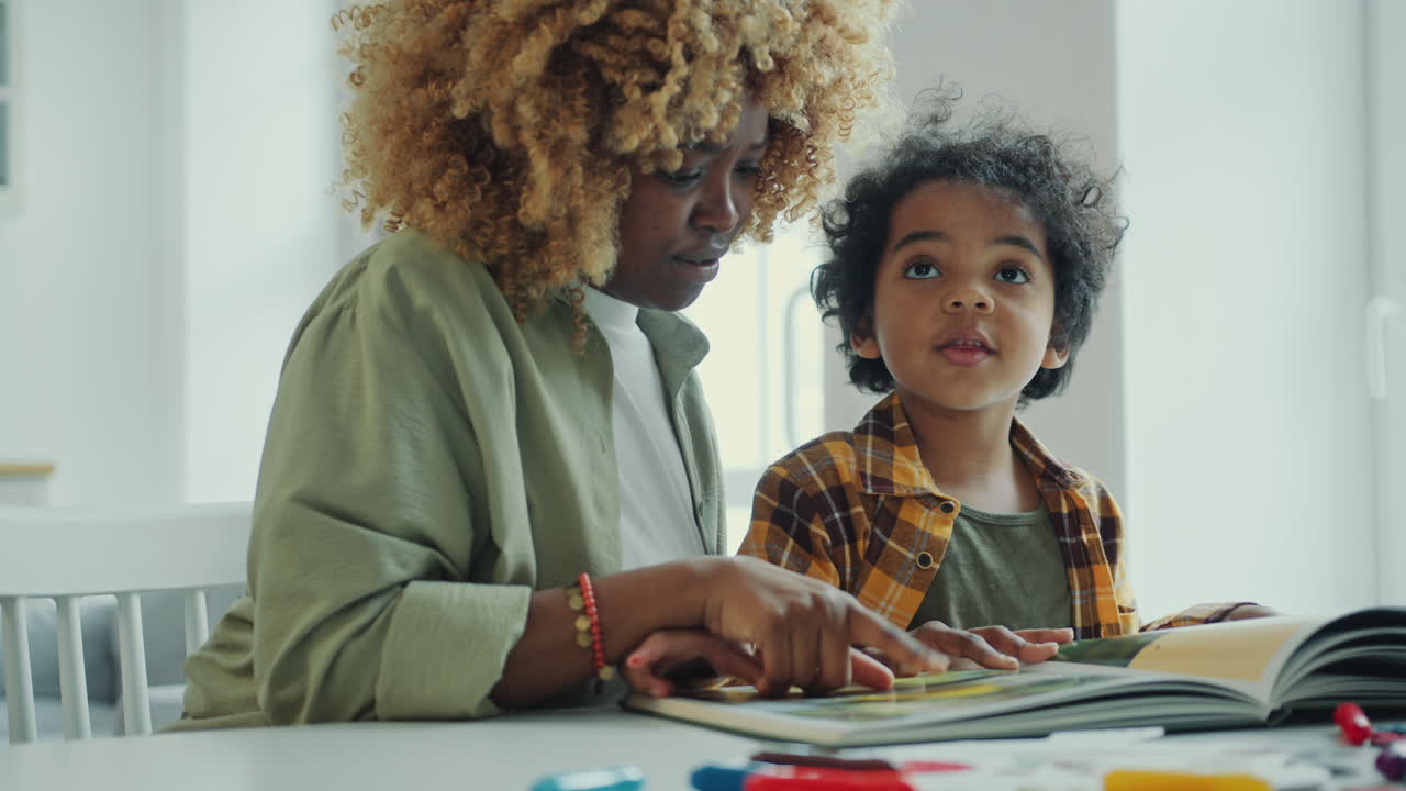 African American Mother and Preschool Son Discussing Pictures Printed in Book
