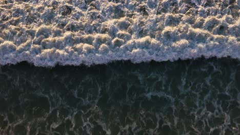 imagen de arriba hacia abajo de la ola chocando contra la orilla, playa de los negros san diego