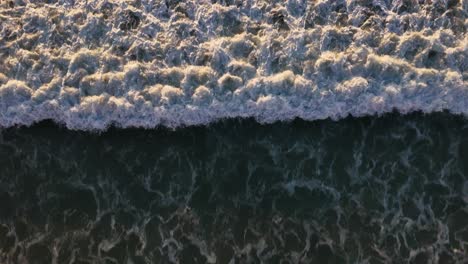 top down shot of wave crashing on shore, blacks beach san diego