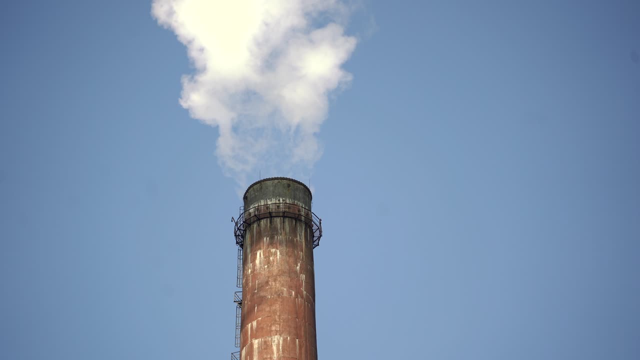 Close up of industrial chimney with emission on the background of a clear blue sky